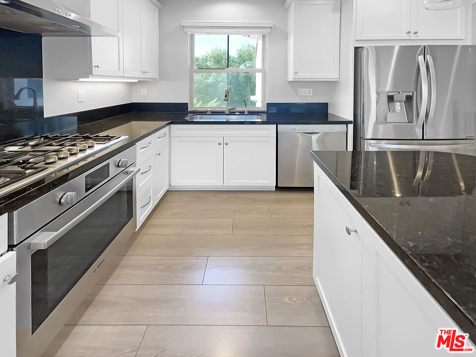 50 Evening Sun Irvine, CA 92620 - Photo 4 of 15 a kitchen with granite countertop a stove a sink and a refrigerator