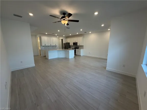 a view of an empty room and kitchen with a sink wooden floor