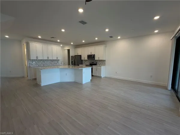 an open kitchen with kitchen island wooden floors granite counter tops and a view of living room