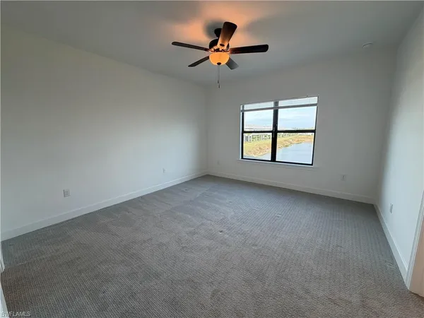 an empty room with windows and ceiling fan