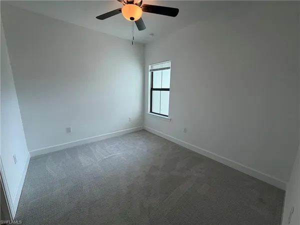 an empty room with closet and a ceiling fan