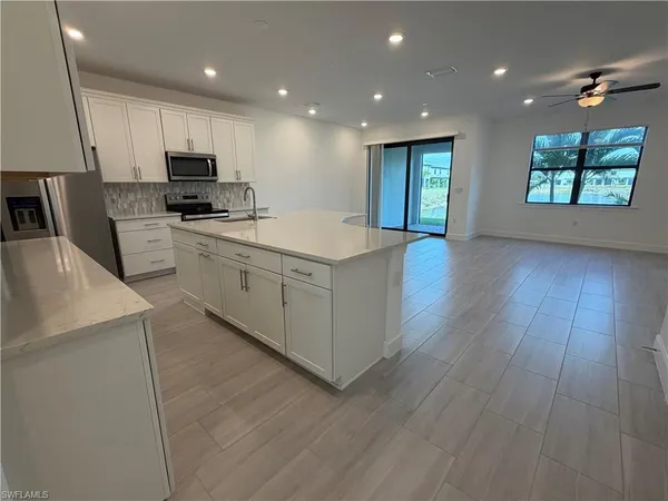 a kitchen with stainless steel appliances granite countertop a refrigerator a sink dishwasher a stove and a microwave oven on the wooden floor