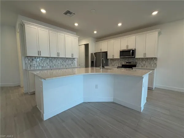 a kitchen with kitchen island granite countertop a sink and a stove top oven