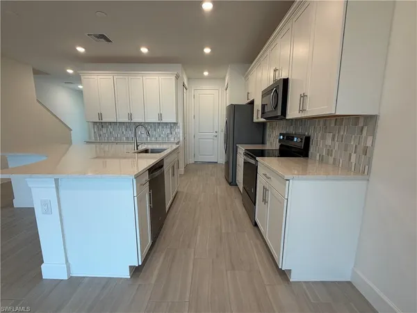 a kitchen with kitchen island granite countertop a sink a counter top space stainless steel appliances and cabinets