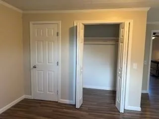 an empty room with wooden floor & closet area