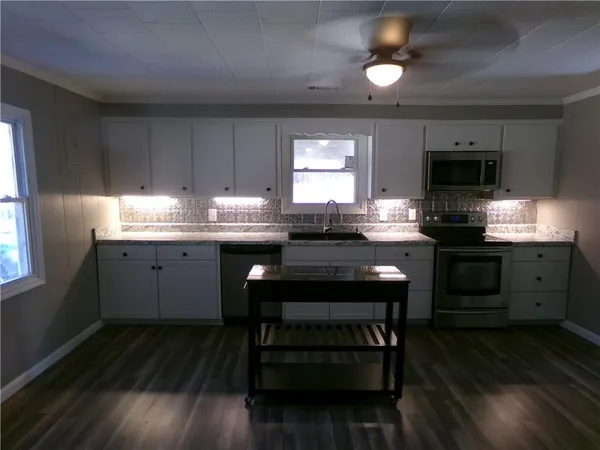 a kitchen with a stove a sink and wooden floor