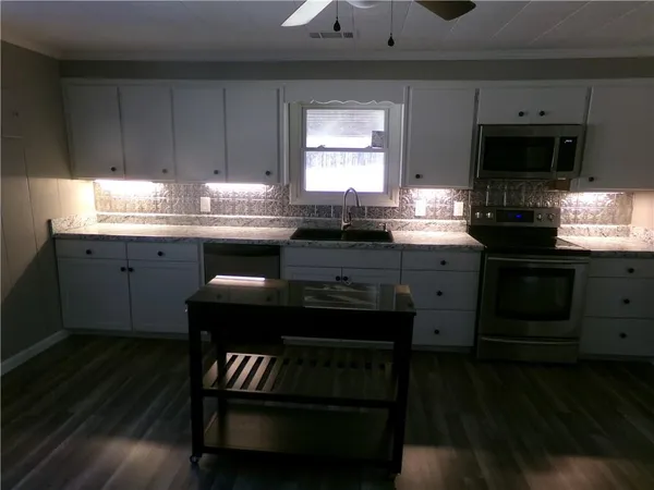 a kitchen with granite countertop stove top oven microwave and cabinets