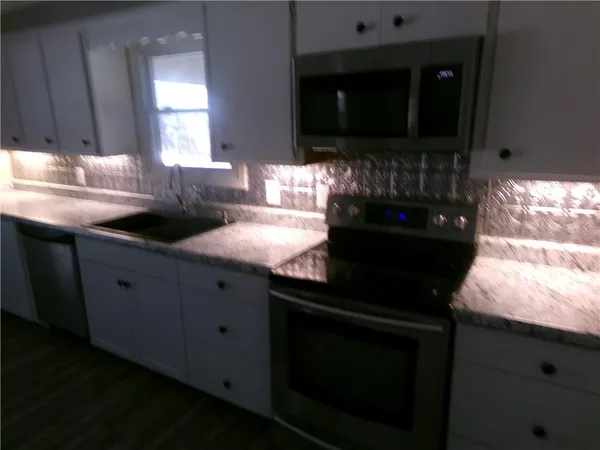 a kitchen with granite countertop white cabinets and black appliances