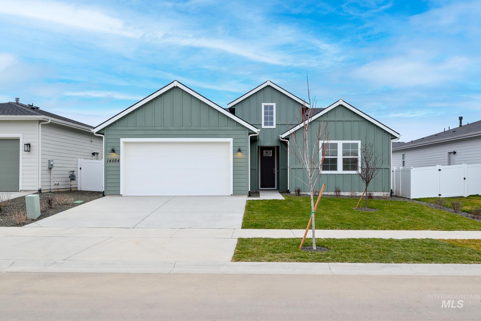Ranch-style house featuring board and batten siding, driveway, a gate, and a garage