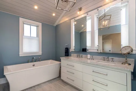 a bathroom with a bathtub a double vanity sink and mirror