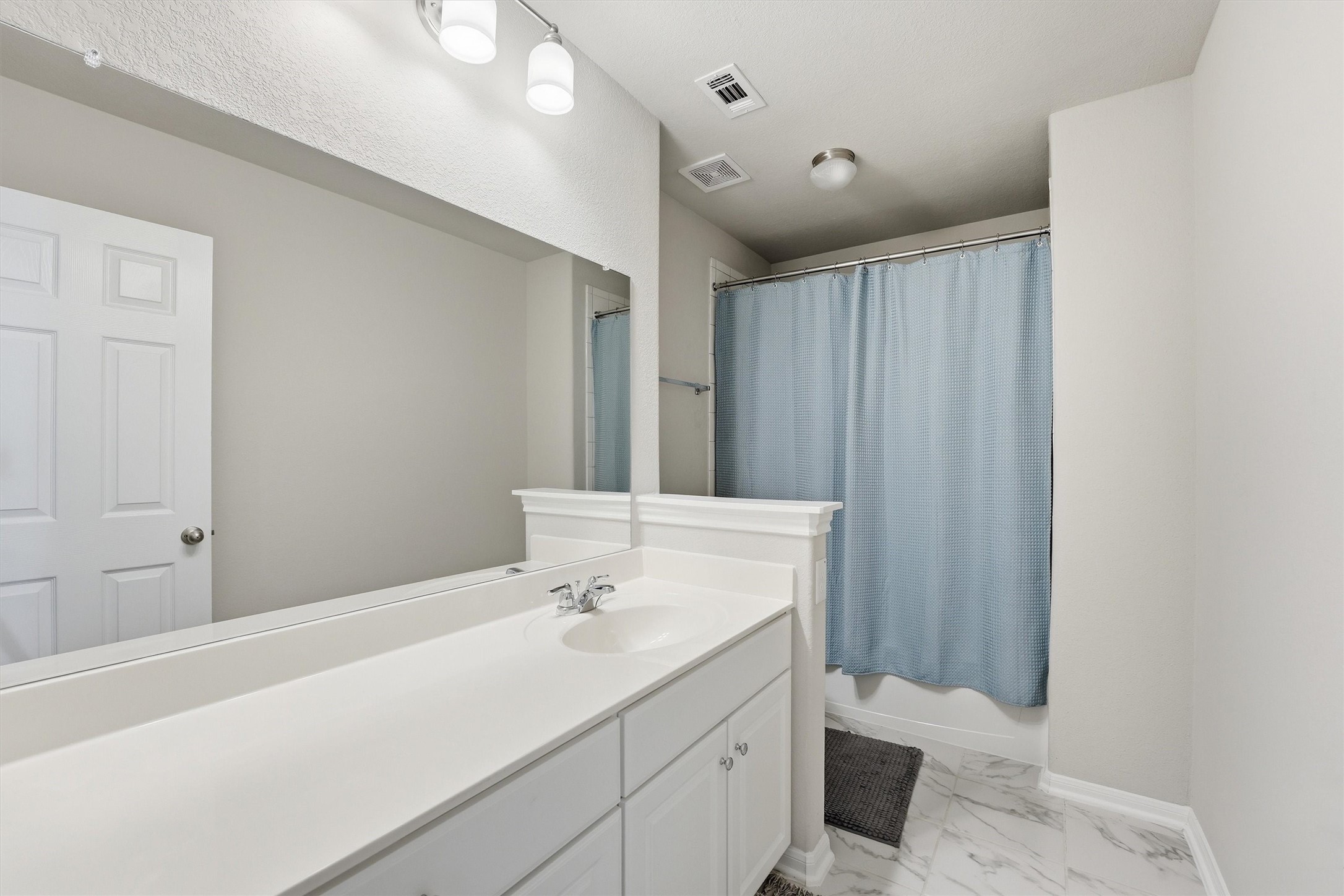 2130 Shellbark Way La Marque, TX 77568 - Photo 17 of 30 Secondary bathroom features a clean, modern design with a large mirror, white vanity, shower and tub combo.
