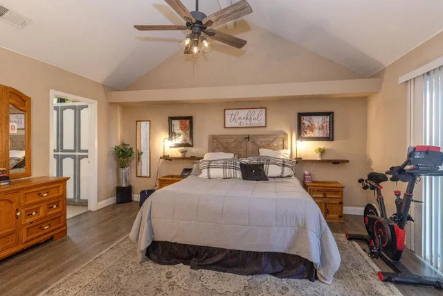 a spacious bedroom with a bed a dresser and a chandelier