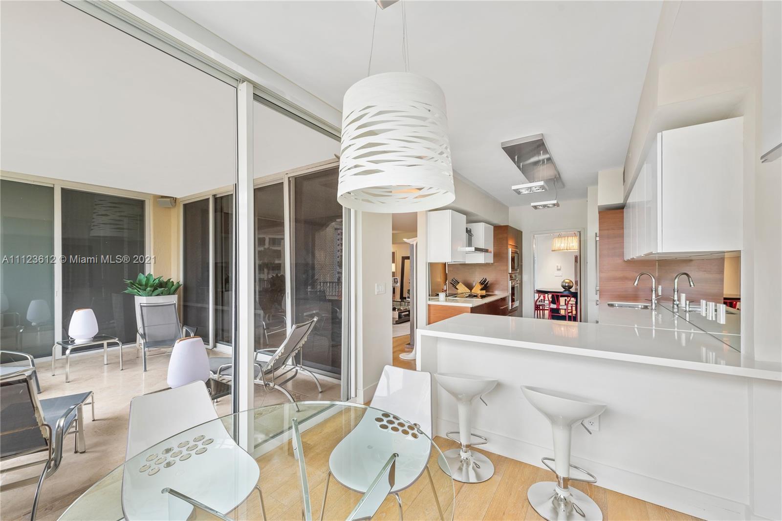 739 Crandon Boulevard, Unit PH1 Key Biscayne, FL 33149 - Photo 14 of 33 a dining room with wooden floor and a chandelier