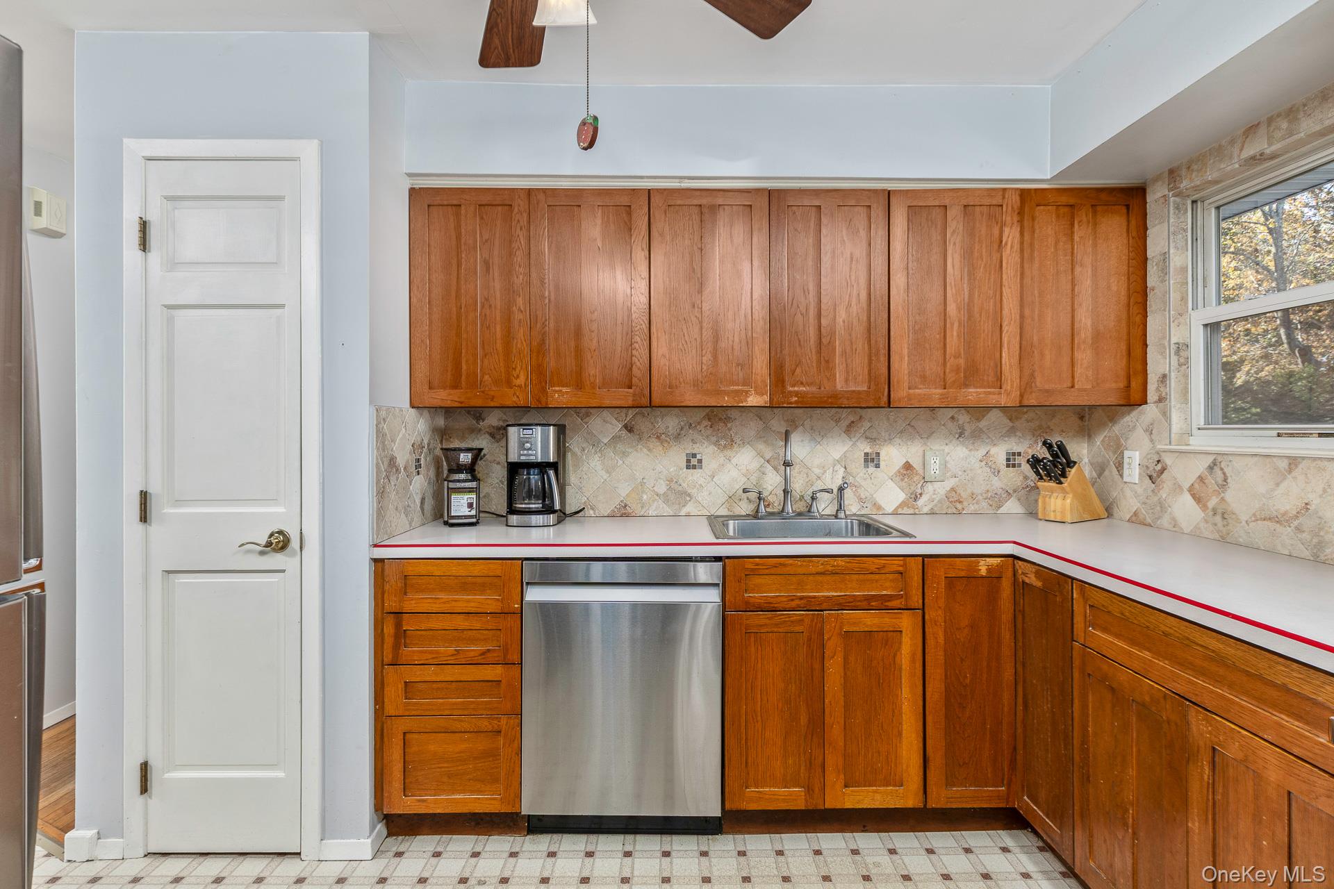 12 Applegate Drive Mastic, NY 11950 - Photo 12 of 29 Kitchen with light countertops, stainless steel dishwasher, brown cabinetry, and tasteful backsplash