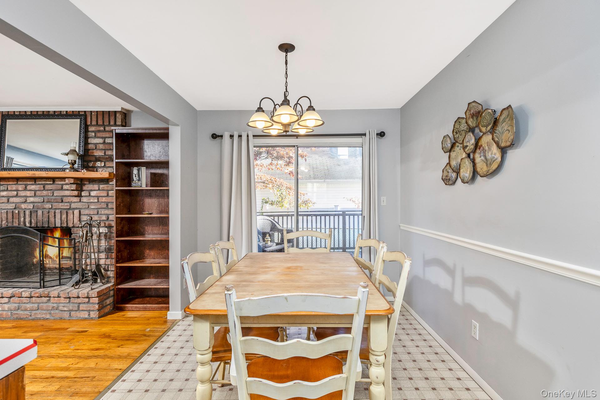 12 Applegate Drive Mastic, NY 11950 - Photo 13 of 29 Dining room with a brick fireplace, a chandelier, and wood finished floors