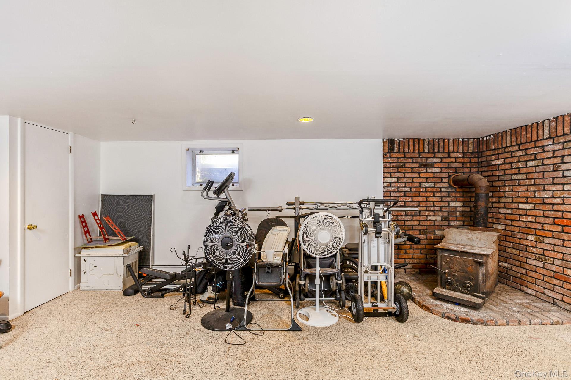 12 Applegate Drive Mastic, NY 11950 - Photo 20 of 29 Game room featuring a wood stove, carpet floors, and brick wall