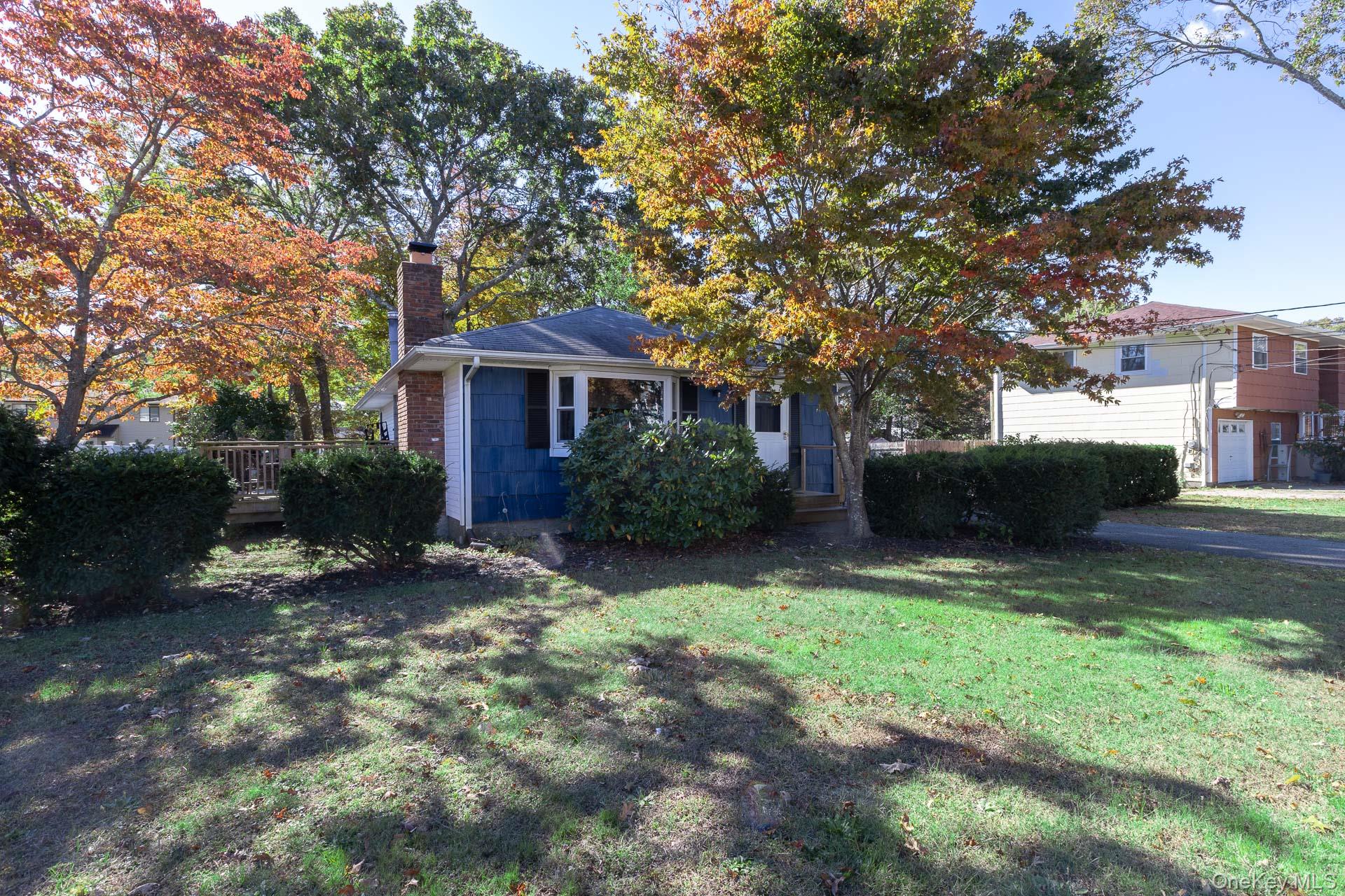 12 Applegate Drive Mastic, NY 11950 - Photo 2 of 29 View of front of house featuring a chimney, a front yard, a wooden deck, and brick siding