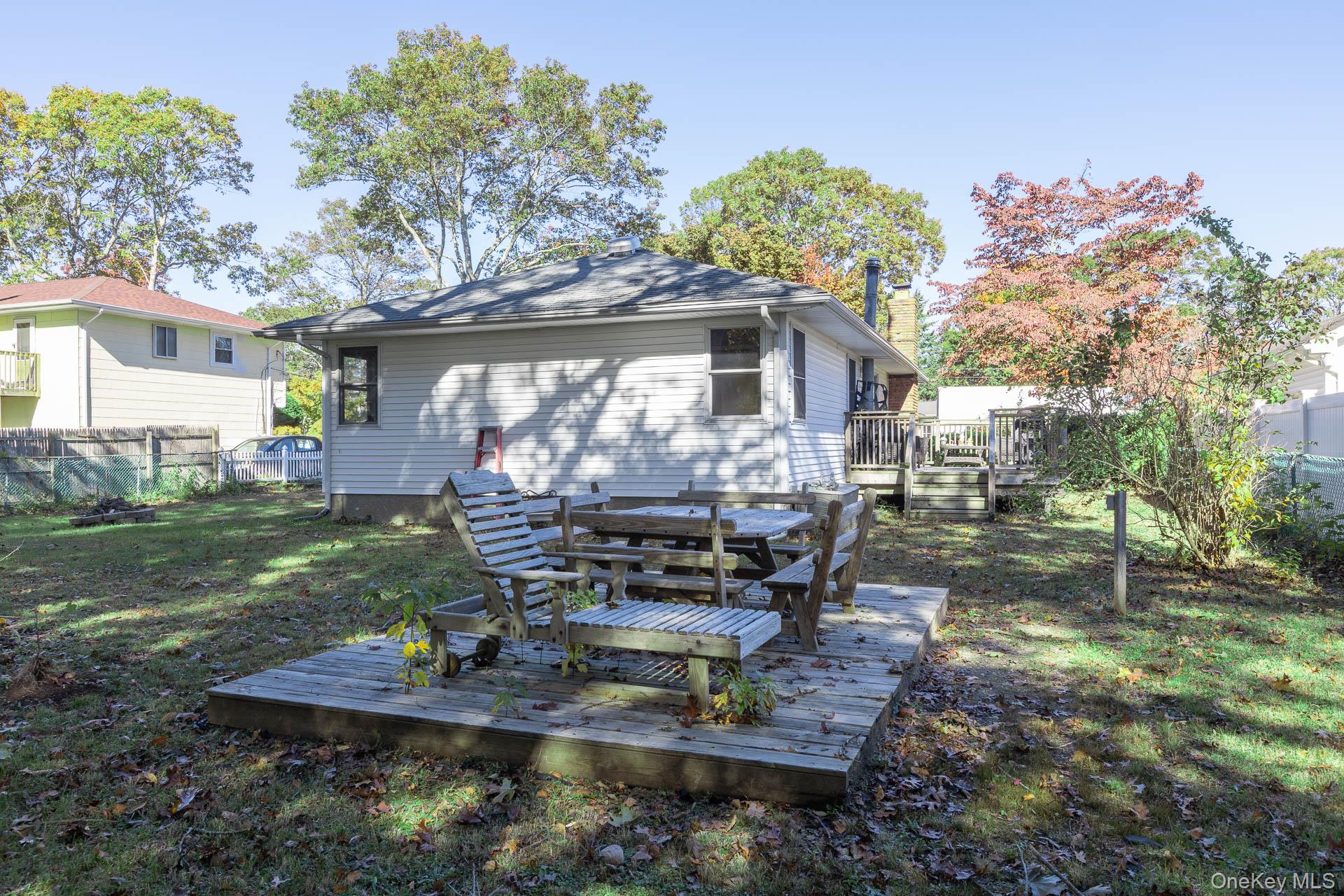 12 Applegate Drive Mastic, NY 11950 - Photo 26 of 29 Back of property with a fenced backyard, a wooden deck, and outdoor dining area