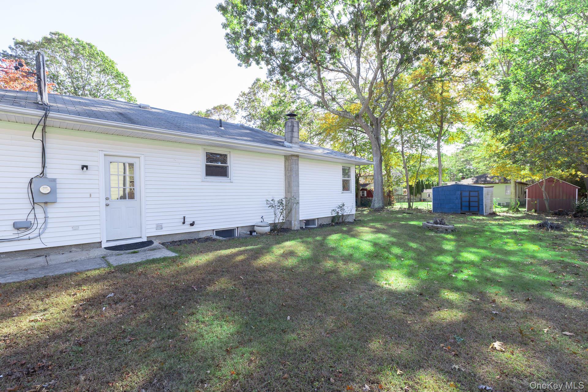 12 Applegate Drive Mastic, NY 11950 - Photo 29 of 29 Back of property featuring a storage shed, a chimney, and a yard