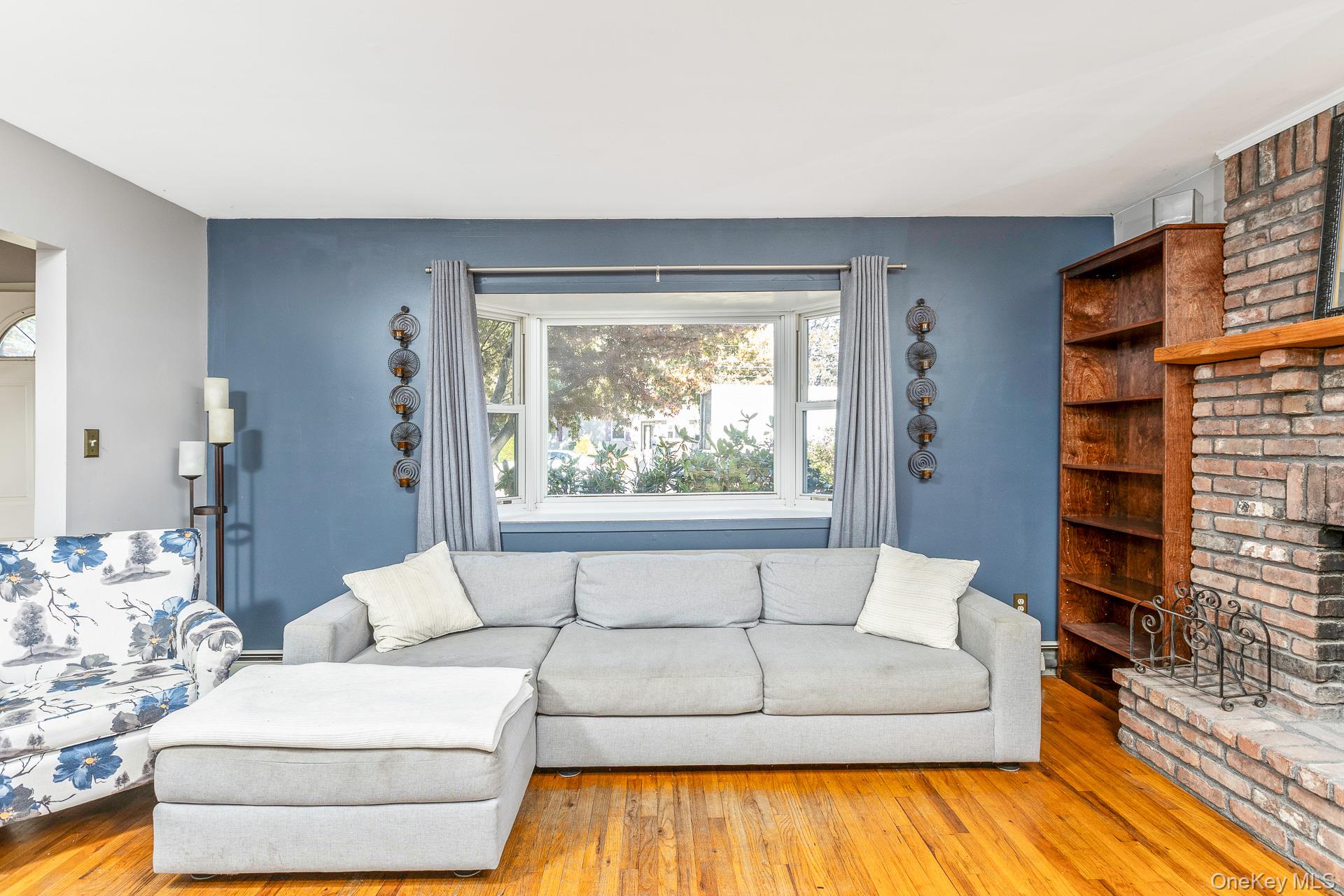 12 Applegate Drive Mastic, NY 11950 - Photo 7 of 29 Living area with wood finished floors and a brick fireplace