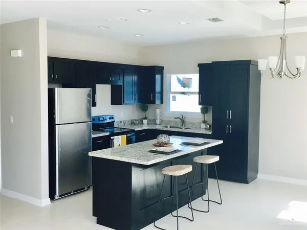 a kitchen with stainless steel appliances granite countertop a refrigerator a sink a stove a microwave and island