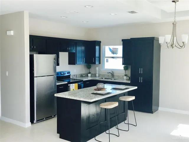 a kitchen with stainless steel appliances granite countertop a refrigerator a sink a stove a microwave and island