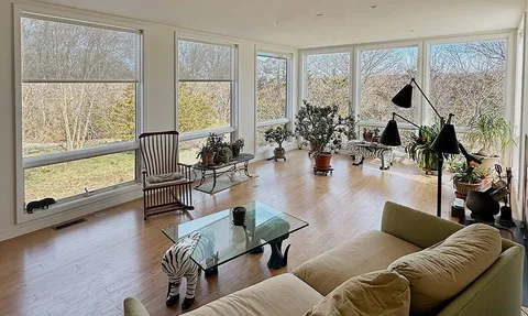 a living room with furniture large window and wooden floor