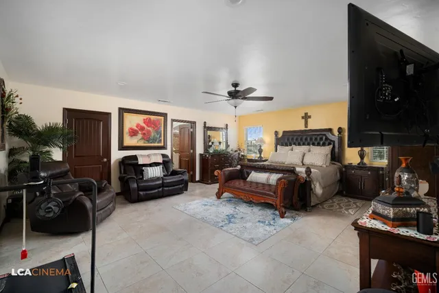 a bedroom with a bed a couch and a flat tv screen on the dresser