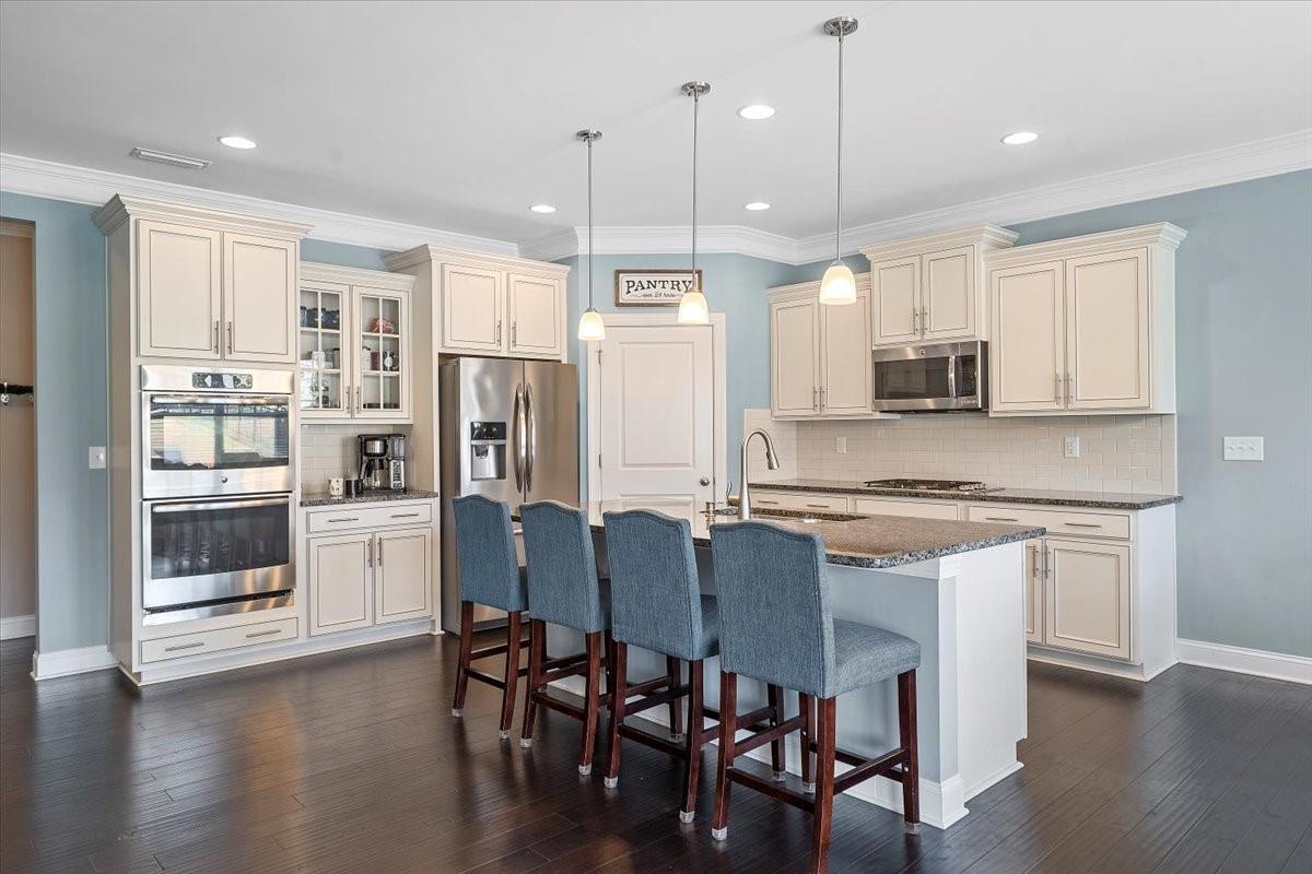 7399 Albemarle Drive Denver, NC 28037 - Photo 9 of 48 a kitchen with stainless steel appliances granite countertop a stove top oven a refrigerator a sink and a dining table with wooden floor