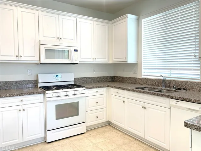 a kitchen with granite countertop white cabinets and white appliances