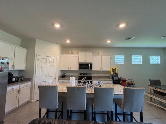 571 Old Country Rd S East Palm Bay, FL 32909 - Photo 5 of 37 a kitchen with a dining table chairs and a refrigerator