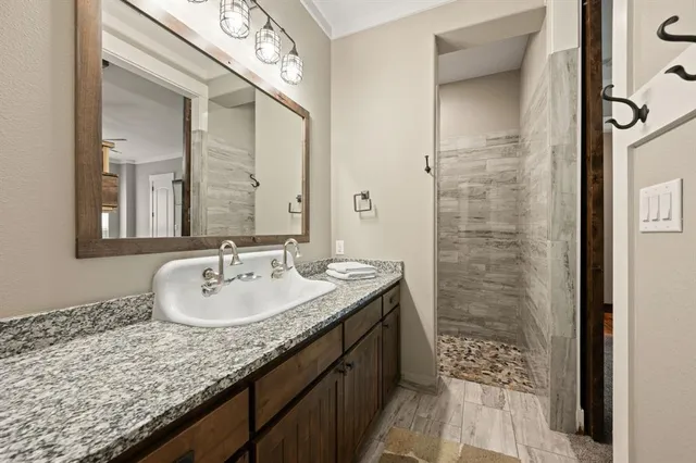 a bathroom with a granite countertop sink a mirror and a shower