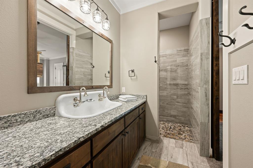 248 Howard Road Valley View, TX 76272 - Photo 22 of 39 a bathroom with a granite countertop sink a mirror and a shower