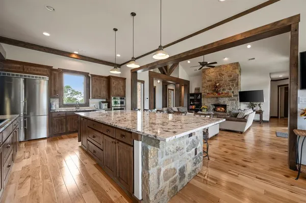 a large kitchen with stainless steel appliances granite countertop plenty wooden cabinets counter space a sink and wooden floor