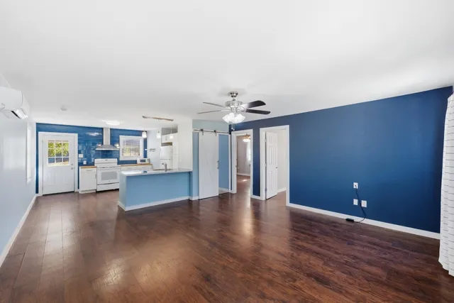 a view of a livingroom with wooden floor and a kitchen space with furniture
