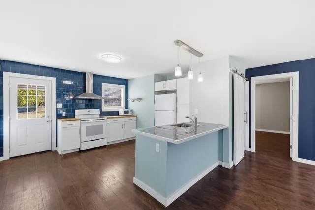 a kitchen with stainless steel appliances a sink a stove a refrigerator cabinets and wooden floor