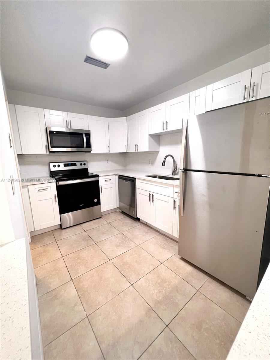 22795 Southwest 66th Avenue, Unit 206 Boca Raton, FL 33428 - Photo 11 of 29 a kitchen with granite countertop a refrigerator and a stove top oven