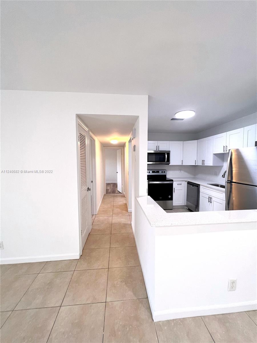 22795 Southwest 66th Avenue, Unit 206 Boca Raton, FL 33428 - Photo 10 of 29 a view of kitchen with refrigerator and white cabinets