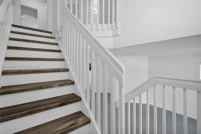 a view of staircase with wooden floor and white walls