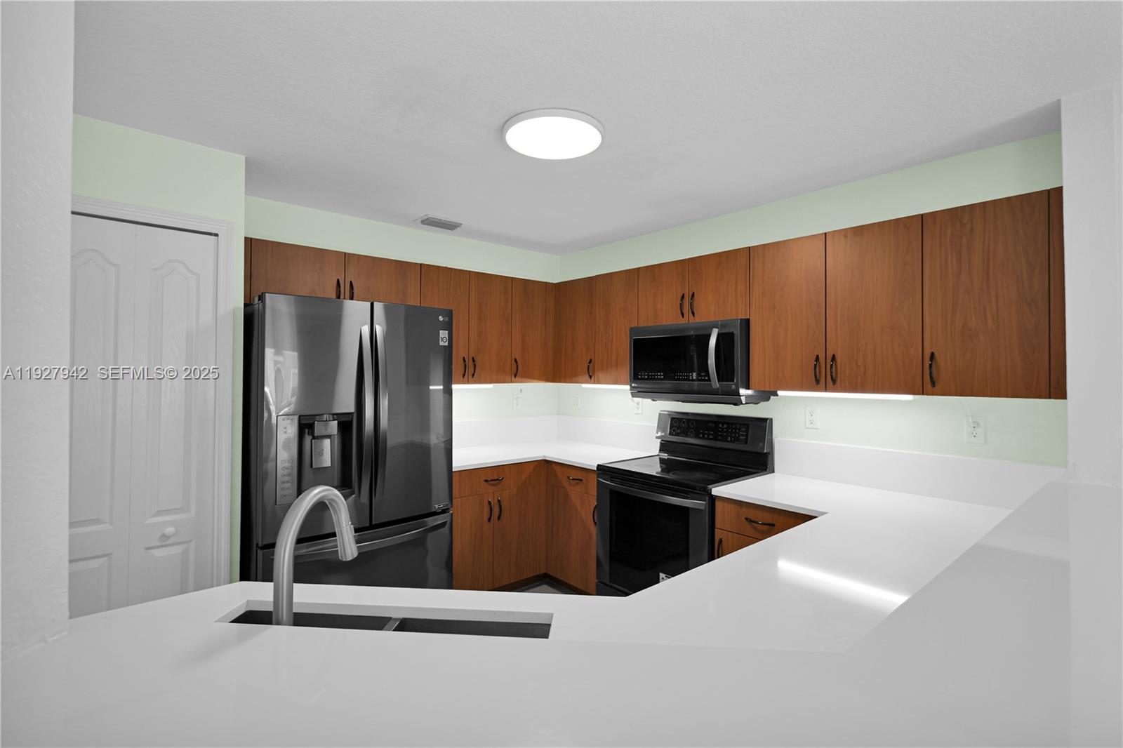 12832 Southwest 30th Street, Unit 118 Miramar, FL 33027 - Photo 7 of 29 a kitchen with stainless steel appliances a refrigerator and microwave