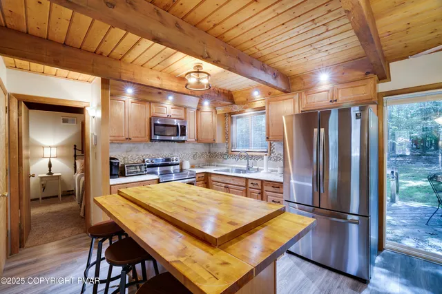 a kitchen with stainless steel appliances granite countertop a refrigerator a sink dishwasher a stove and a refrigerator with wooden floor