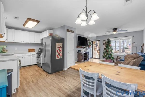 a kitchen with stainless steel appliances kitchen island granite countertop a refrigerator a stove a sink dishwasher and white cabinets with wooden floor