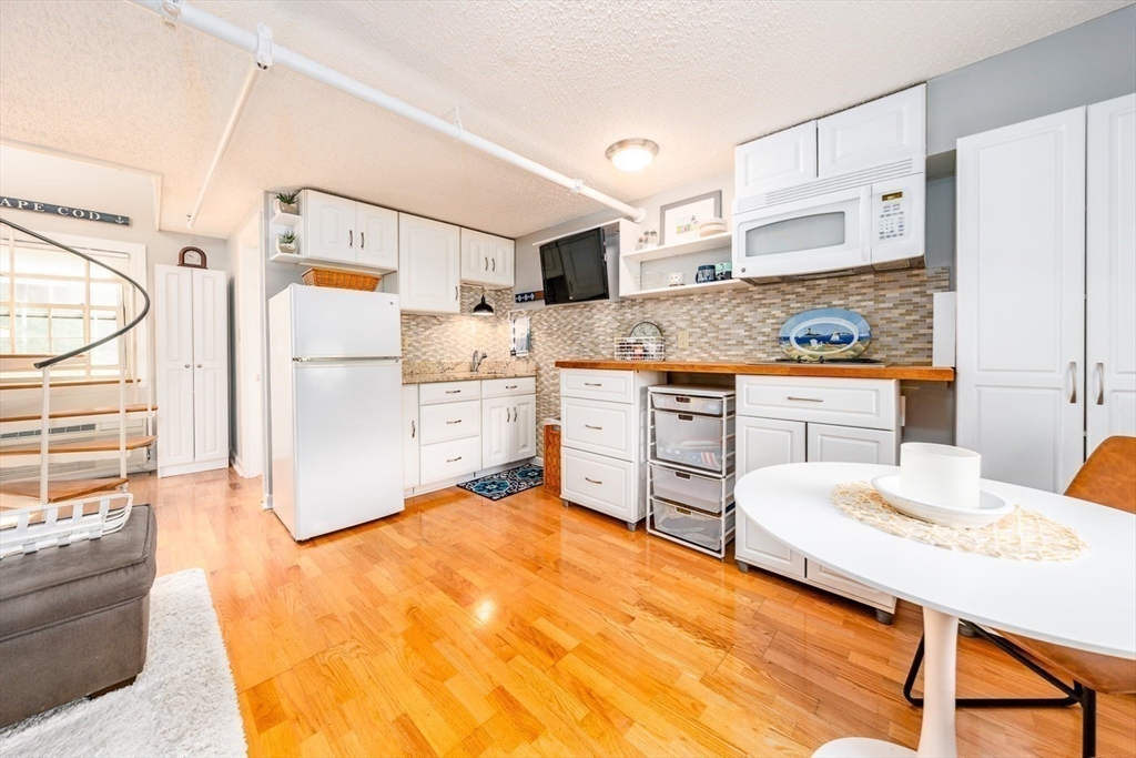 141 Main Street, Unit TH1 Dennis, MA 02660 - Photo 7 of 27 a kitchen with stainless steel appliances kitchen island a refrigerator sink and white cabinets