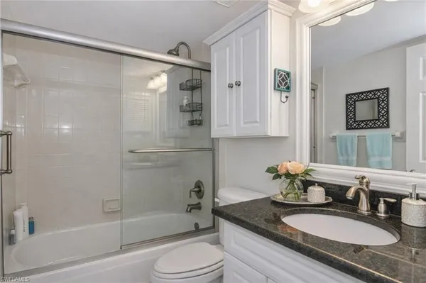 a bathroom with a granite countertop sink toilet and shower