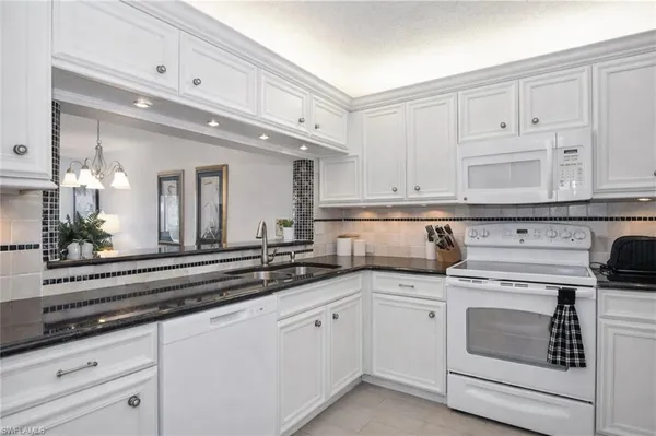 a kitchen with white cabinets and white appliances