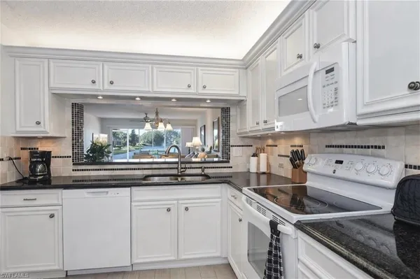a kitchen with white cabinets and white appliances