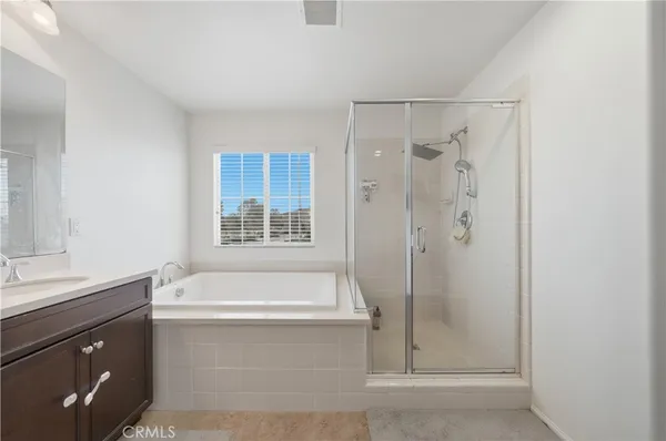 a bathroom with a tub sink double vanity and a shower
