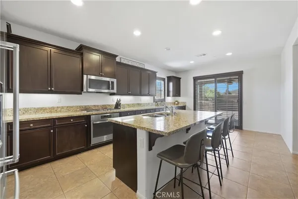 a large kitchen with kitchen island granite countertop wooden cabinets and stainless steel appliances