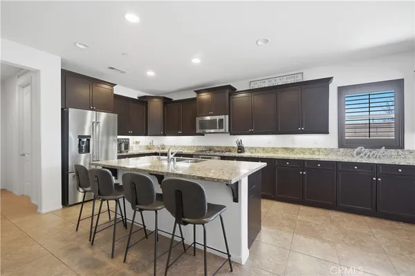 a kitchen with stainless steel appliances granite countertop a table chairs sink refrigerator and cabinets