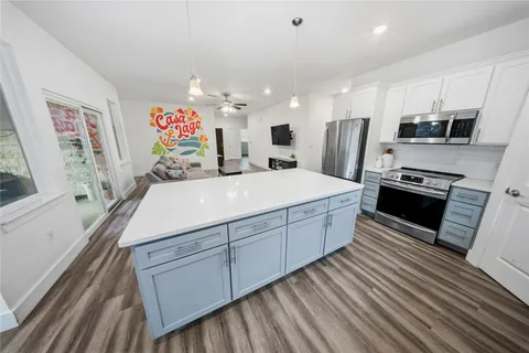 a large kitchen with stainless steel appliances a large counter top a stove a chimney a sink and a refrigerator